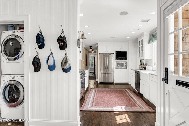 kitchen with appliances with stainless steel finishes, white cabinets, stacked washer / drying machine, and dark hardwood / wood-style floors