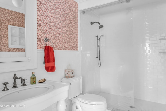 bathroom featuring toilet, sink, and a tile shower