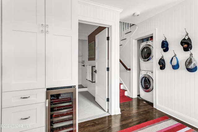 clothes washing area featuring stacked washer / dryer, dark hardwood / wood-style flooring, indoor bar, and beverage cooler