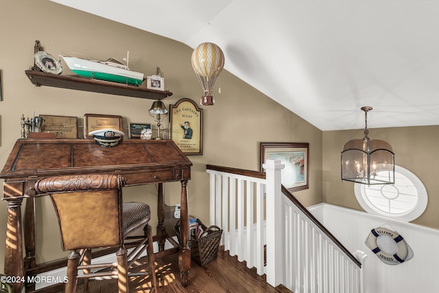 staircase featuring vaulted ceiling, an inviting chandelier, and hardwood / wood-style floors