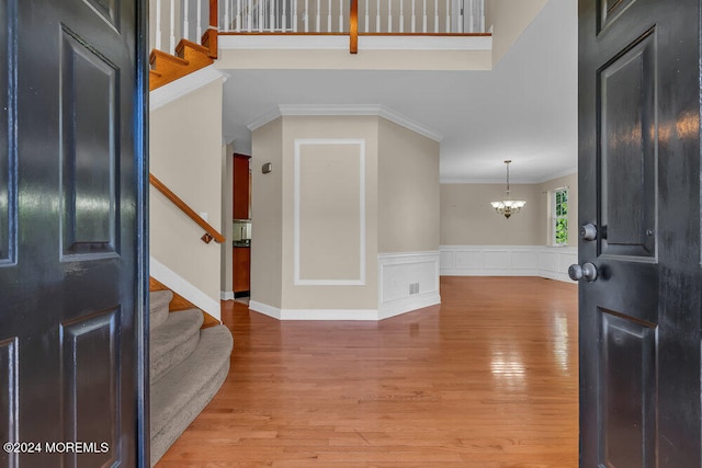 entrance foyer with ornamental molding, a chandelier, and light wood-type flooring