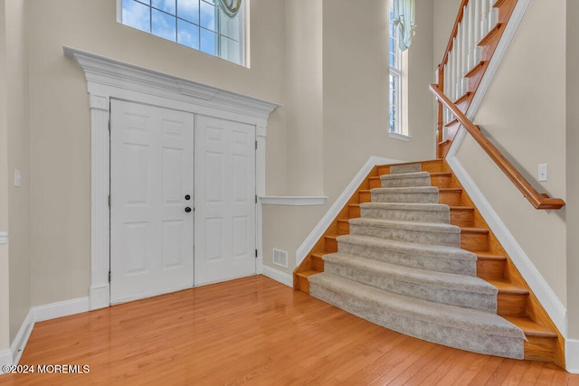 entrance foyer with hardwood / wood-style flooring and a towering ceiling