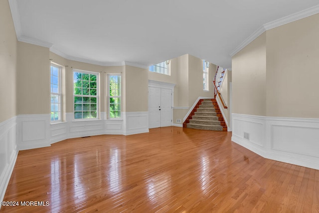 unfurnished living room featuring ornamental molding and light wood-type flooring