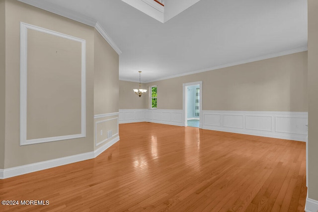 empty room featuring crown molding, a chandelier, and hardwood / wood-style floors