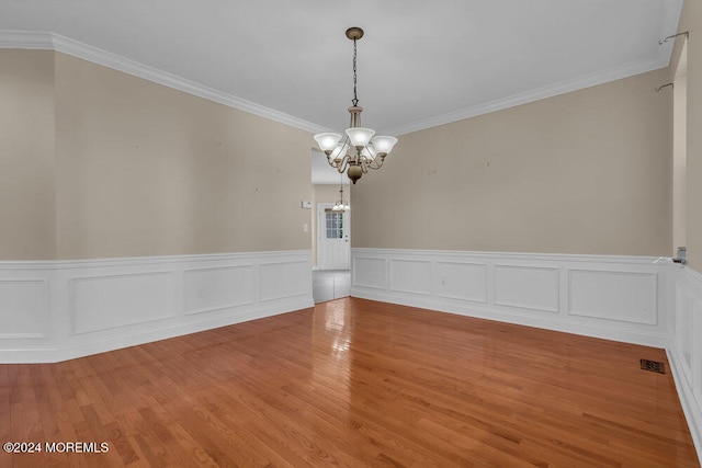 unfurnished room featuring crown molding, a notable chandelier, and wood-type flooring