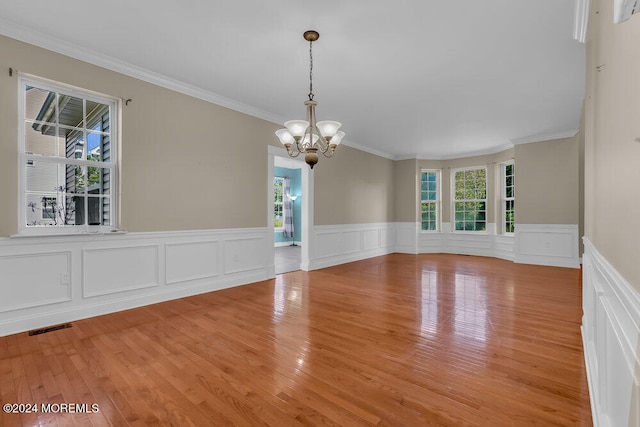 spare room with light hardwood / wood-style floors, an inviting chandelier, and ornamental molding