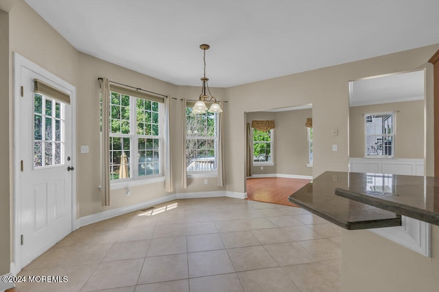 unfurnished dining area featuring a healthy amount of sunlight, a chandelier, and light tile patterned floors