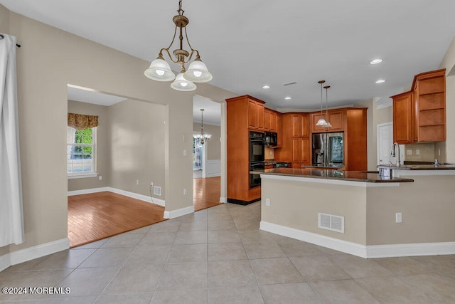 kitchen with black appliances, light hardwood / wood-style flooring, kitchen peninsula, and decorative light fixtures