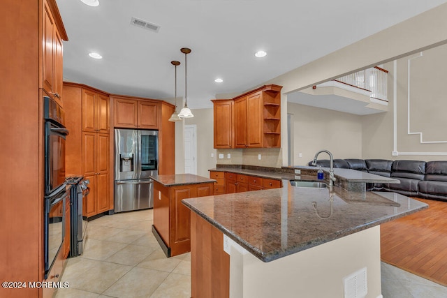 kitchen with sink, a kitchen island, light hardwood / wood-style floors, dark stone counters, and stainless steel fridge with ice dispenser