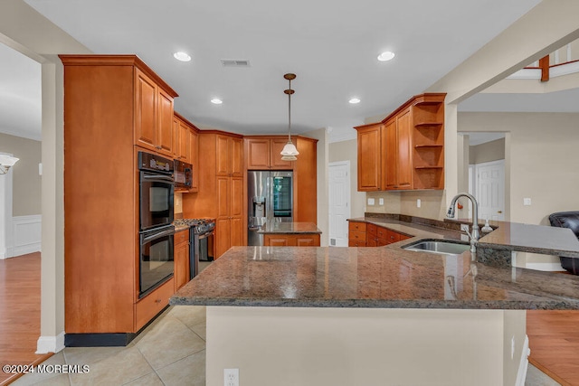 kitchen with sink, light wood-type flooring, stainless steel fridge, decorative light fixtures, and black double oven