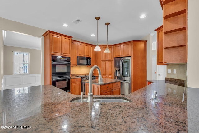 kitchen with kitchen peninsula, dark stone countertops, sink, black appliances, and pendant lighting