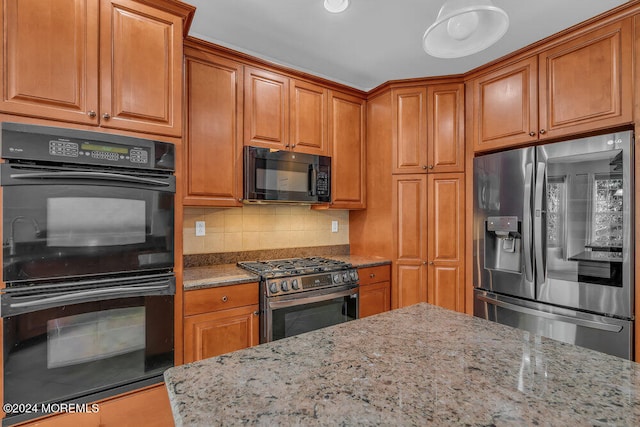 kitchen with light stone countertops, black appliances, and decorative backsplash