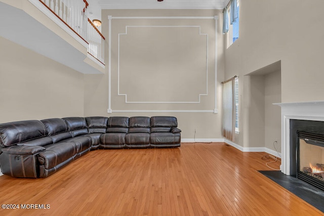 unfurnished living room with ornamental molding, hardwood / wood-style flooring, and a towering ceiling