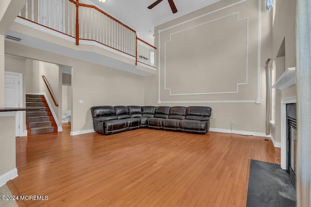 unfurnished living room featuring a towering ceiling, hardwood / wood-style flooring, and ceiling fan