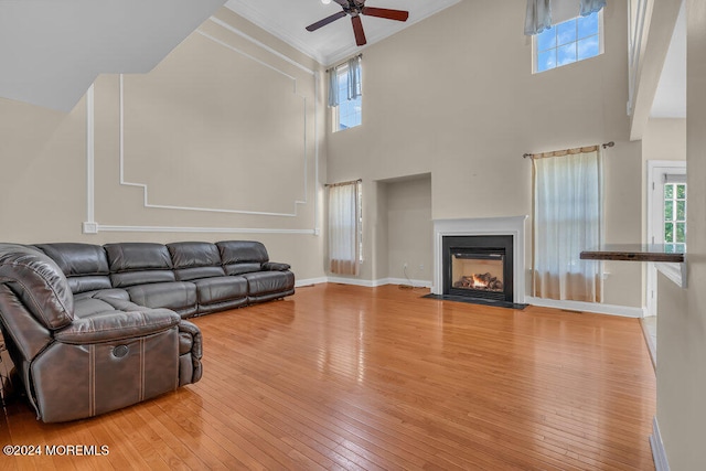 living room featuring ceiling fan, wood-type flooring, a high ceiling, and a wealth of natural light