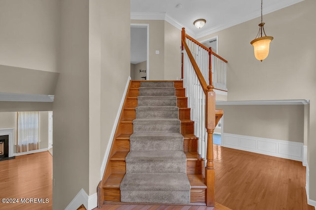 staircase featuring ornamental molding and hardwood / wood-style flooring