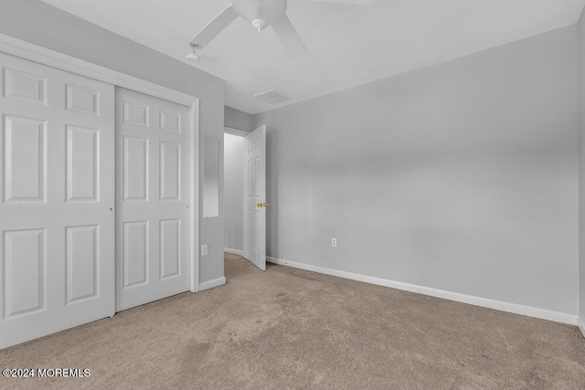 unfurnished bedroom with light colored carpet, a closet, and ceiling fan