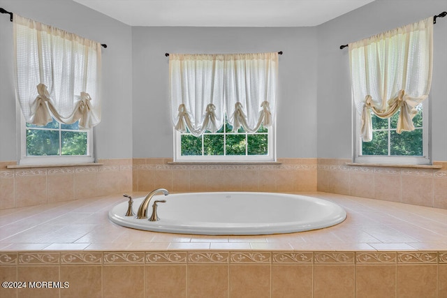 bathroom with tiled bath and a healthy amount of sunlight