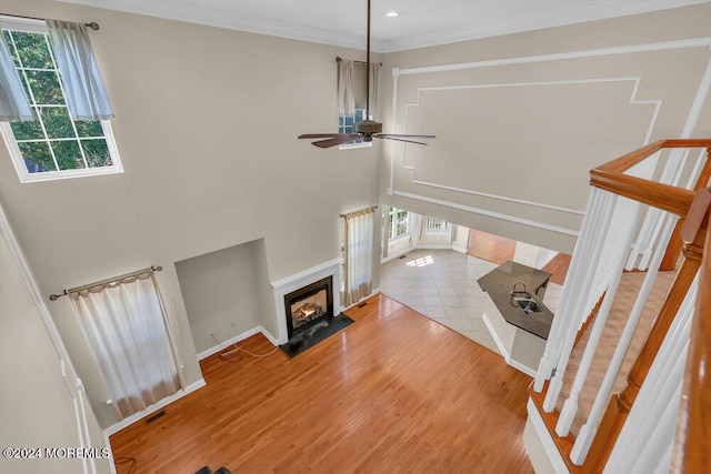 living room with ceiling fan, ornamental molding, and light hardwood / wood-style flooring