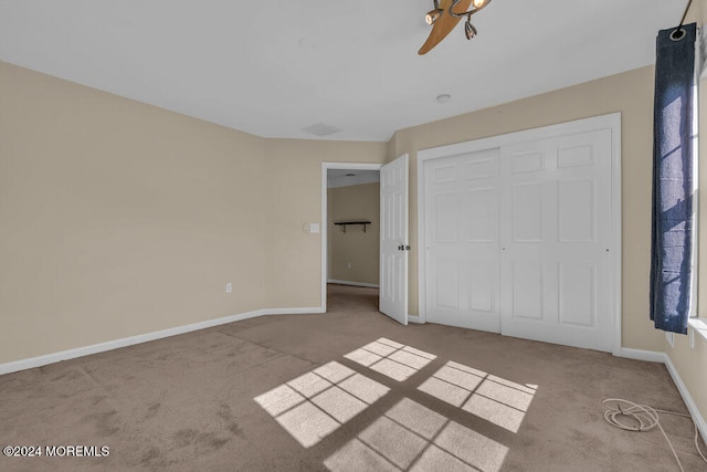 unfurnished bedroom with light colored carpet and a closet