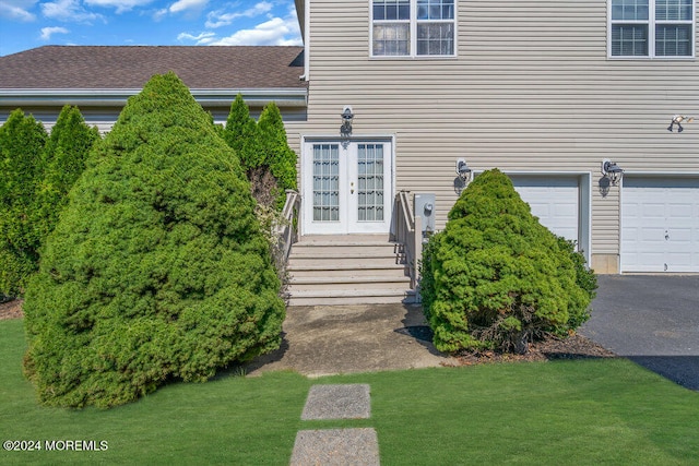 property entrance with french doors, a garage, and a lawn