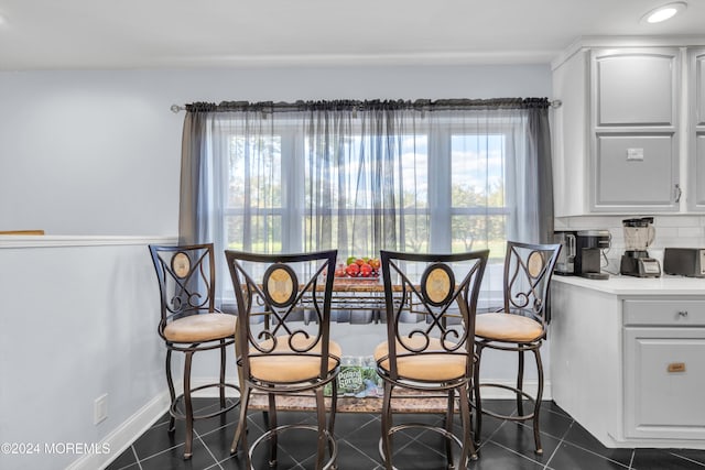 dining space featuring dark tile patterned flooring and plenty of natural light