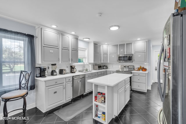 kitchen featuring sink, a kitchen island, backsplash, dark tile patterned floors, and stainless steel appliances