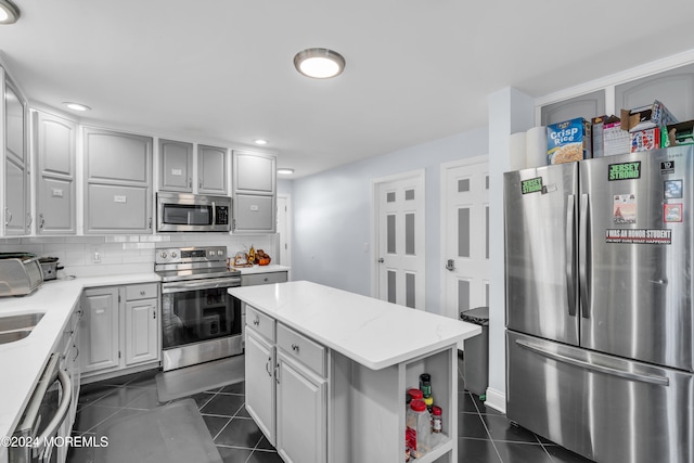 kitchen with tasteful backsplash, appliances with stainless steel finishes, a center island, and dark tile patterned floors