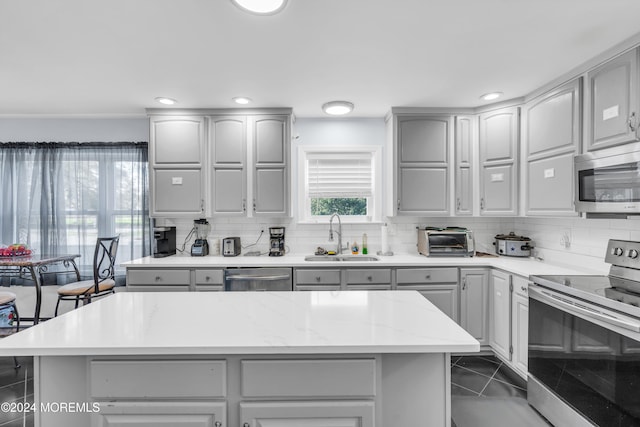 kitchen featuring gray cabinetry, stainless steel appliances, sink, and dark tile patterned flooring