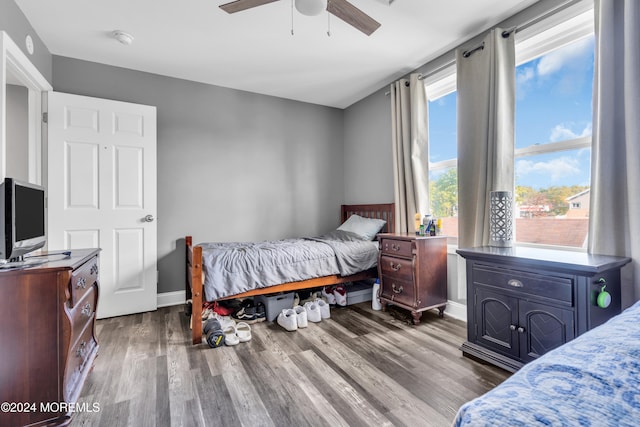 bedroom with ceiling fan, multiple windows, and dark hardwood / wood-style flooring