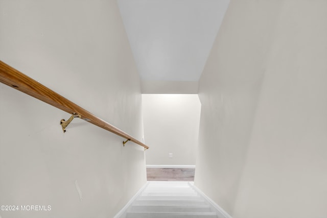 staircase with lofted ceiling and hardwood / wood-style floors