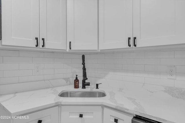 kitchen with backsplash, light stone countertops, sink, and white cabinets