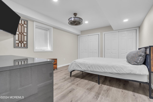 bedroom with multiple closets and light wood-type flooring