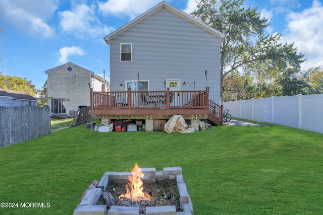 back of property featuring an outdoor fire pit, a deck, and a yard