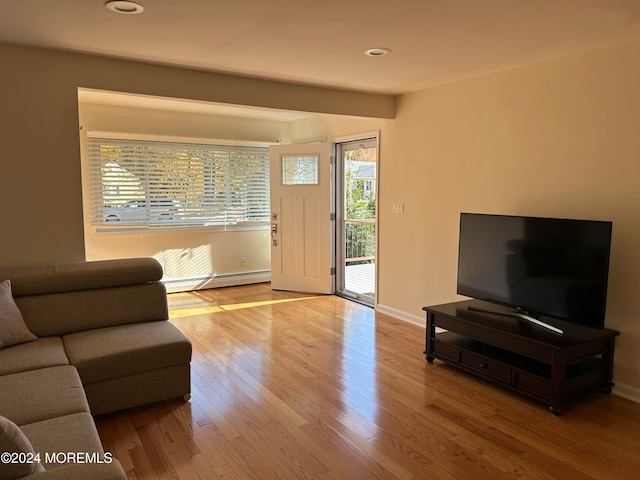 living room featuring light hardwood / wood-style floors, beam ceiling, and a baseboard heating unit