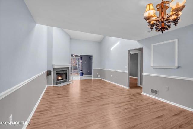 unfurnished living room featuring a fireplace, a notable chandelier, and light hardwood / wood-style flooring