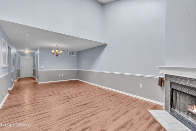 unfurnished living room featuring a fireplace, an inviting chandelier, and light hardwood / wood-style flooring