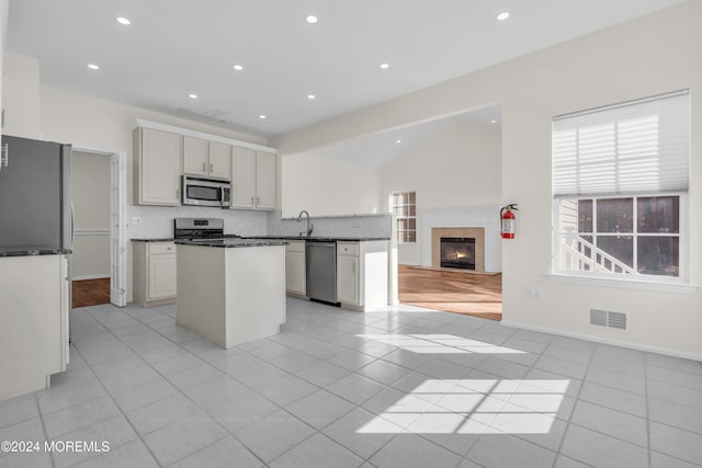 kitchen featuring lofted ceiling, backsplash, sink, light tile patterned floors, and appliances with stainless steel finishes