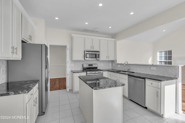 kitchen featuring appliances with stainless steel finishes, sink, a center island, white cabinetry, and light hardwood / wood-style floors