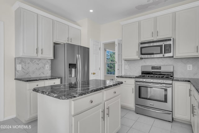 kitchen with stainless steel appliances, tasteful backsplash, a center island, and white cabinets