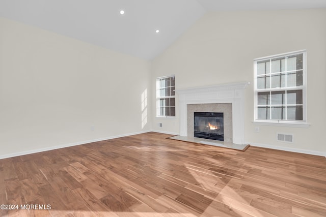 unfurnished living room with a fireplace, high vaulted ceiling, and light hardwood / wood-style floors