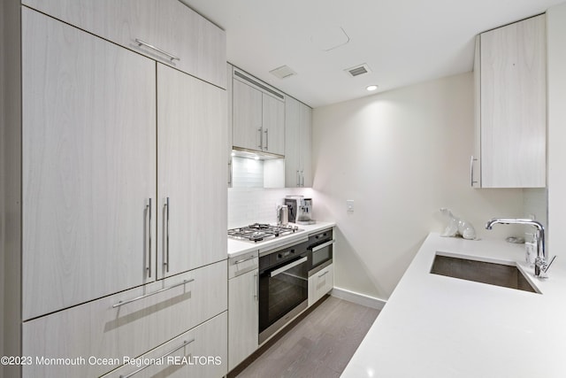 kitchen with decorative backsplash, sink, appliances with stainless steel finishes, and light hardwood / wood-style flooring