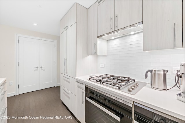 kitchen with white cabinets, dark hardwood / wood-style floors, tasteful backsplash, and stainless steel appliances