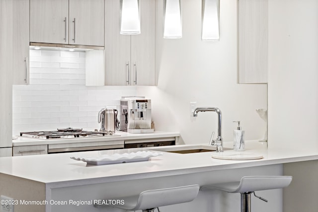 kitchen with sink, a breakfast bar, pendant lighting, and ventilation hood