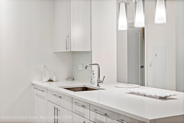 kitchen with tasteful backsplash, sink, and hanging light fixtures