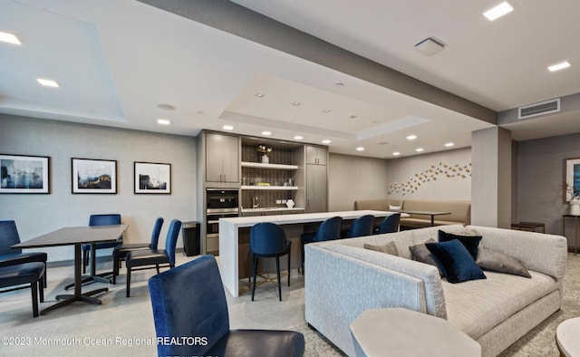 living room featuring a raised ceiling and light colored carpet