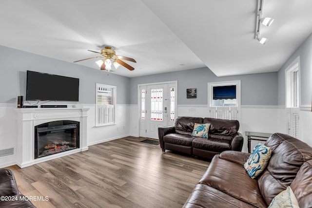 living room featuring rail lighting, ceiling fan, and light wood-type flooring