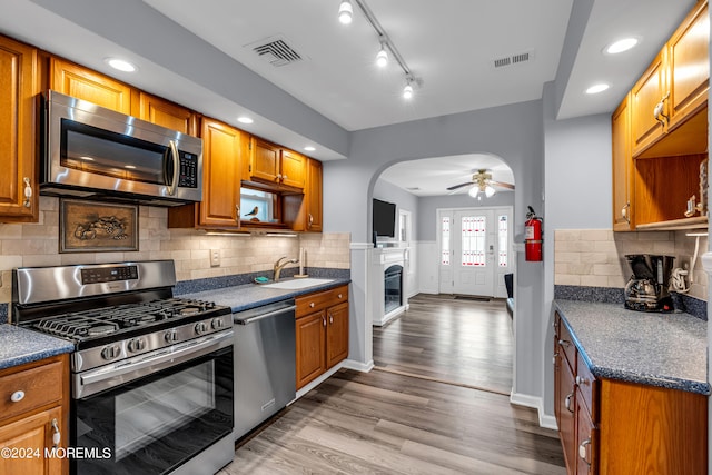 kitchen featuring decorative backsplash, stainless steel appliances, sink, light hardwood / wood-style floors, and ceiling fan