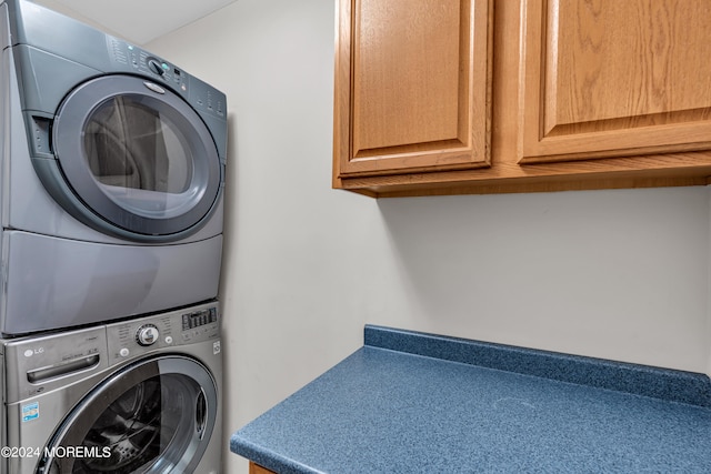 laundry area with stacked washer and clothes dryer and cabinets