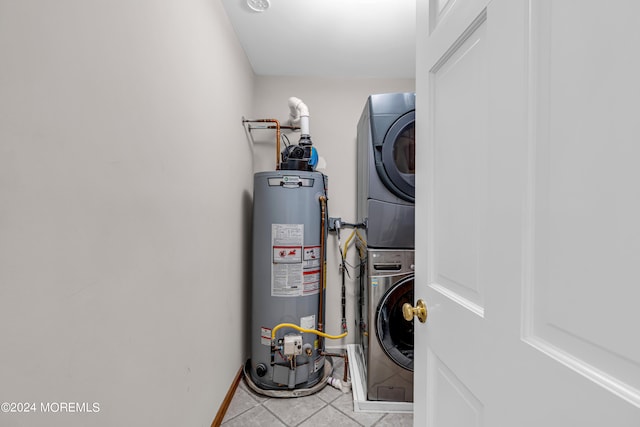 clothes washing area featuring gas water heater, light tile patterned flooring, and stacked washer and clothes dryer